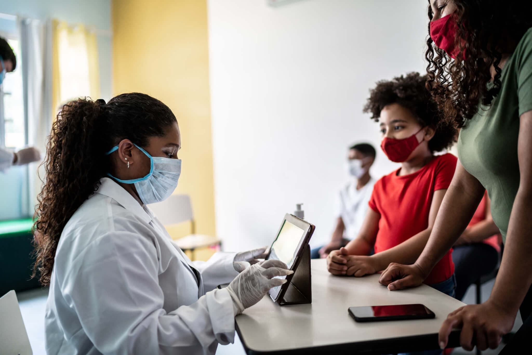 Women with mask on talking to women with mask on, in clinical setting