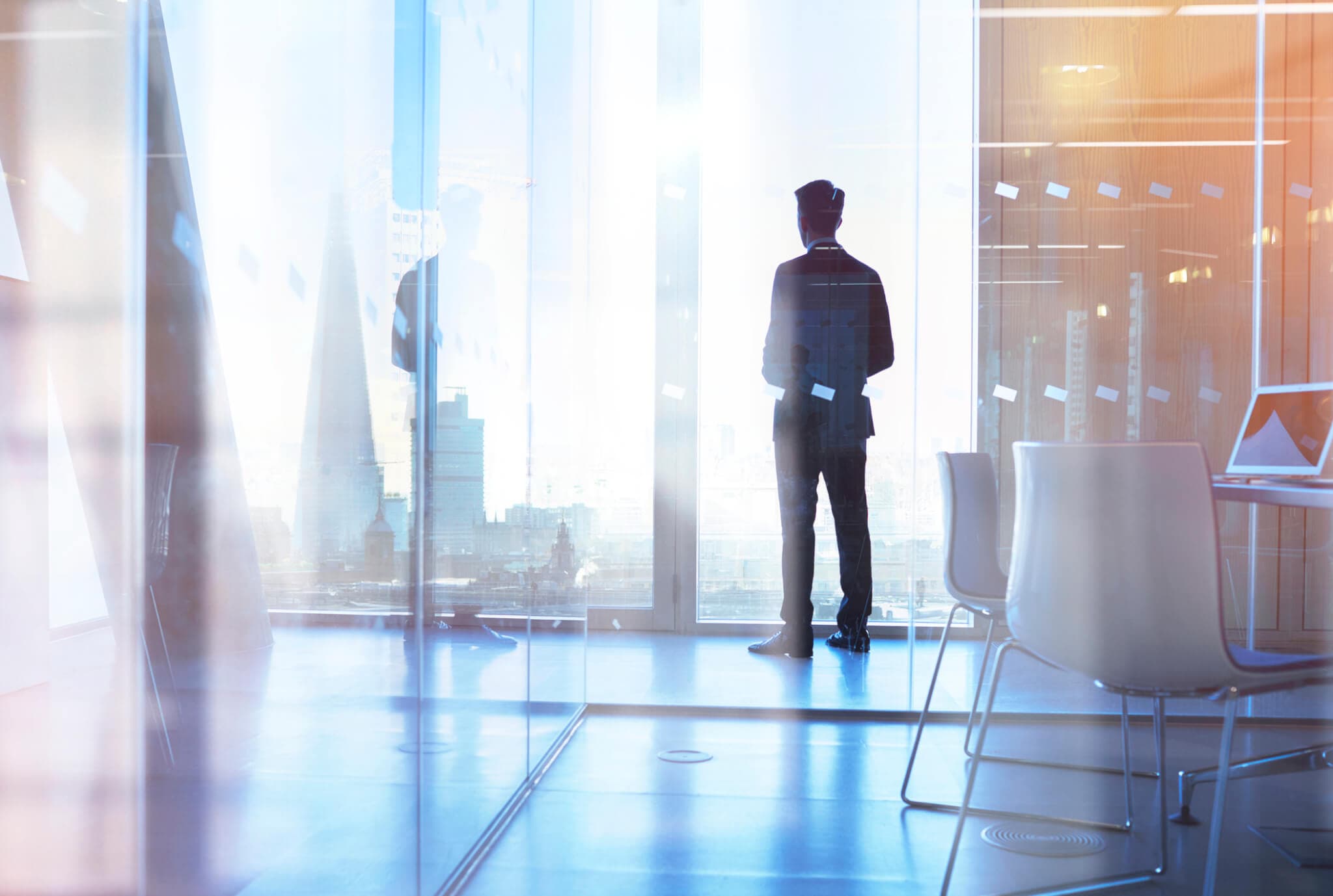 Businessman looking out of office over city through a high up office window