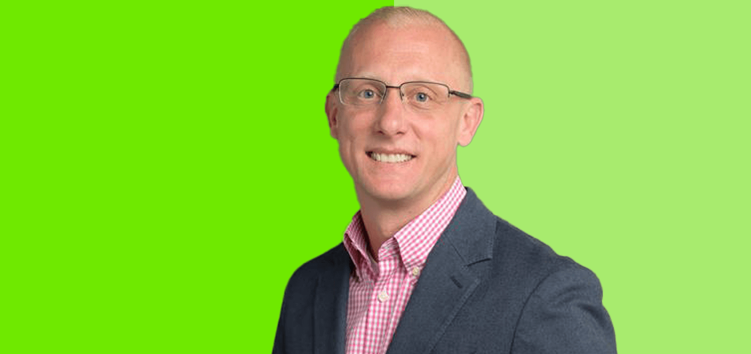 Image of a man with a button up shirt and blazer wearing glasses, smiling direct to camera