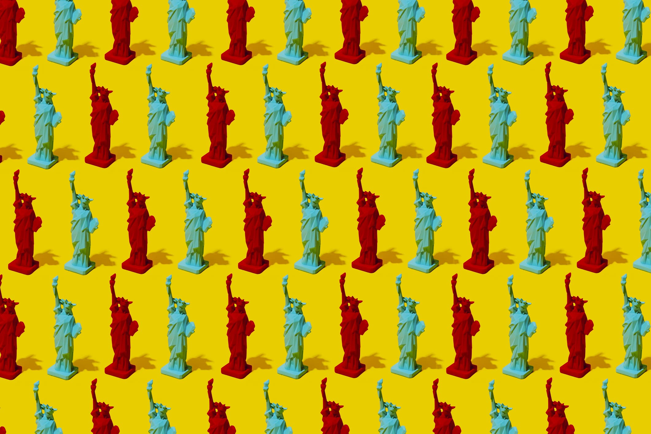 a pattern of several statues of liberty, red and blue, as the colors of the republican party and the democratic party, on a yellow background