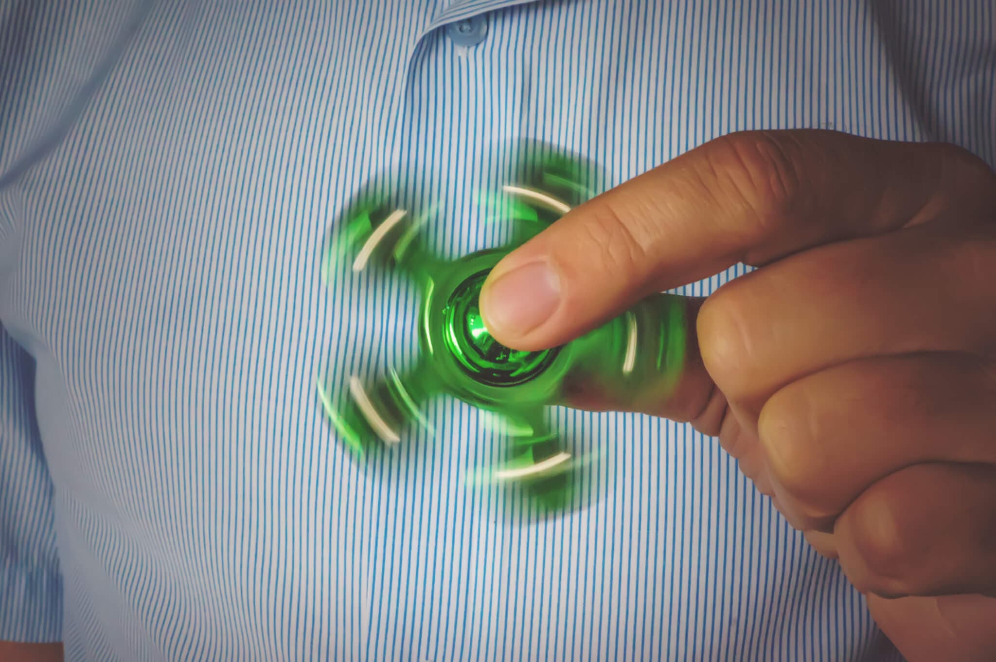 fingers of the men holding the spinner close up. A guy in a business suit and a white shirt. Businessman relieves stress at work. Powerful spinner, Twister for hands entertainment rotating toy.