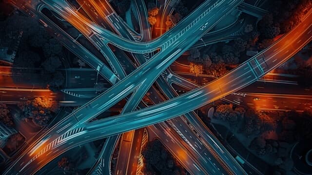 Aerial visual of multiple large roads converging at nighttime, blurred with cars in motion