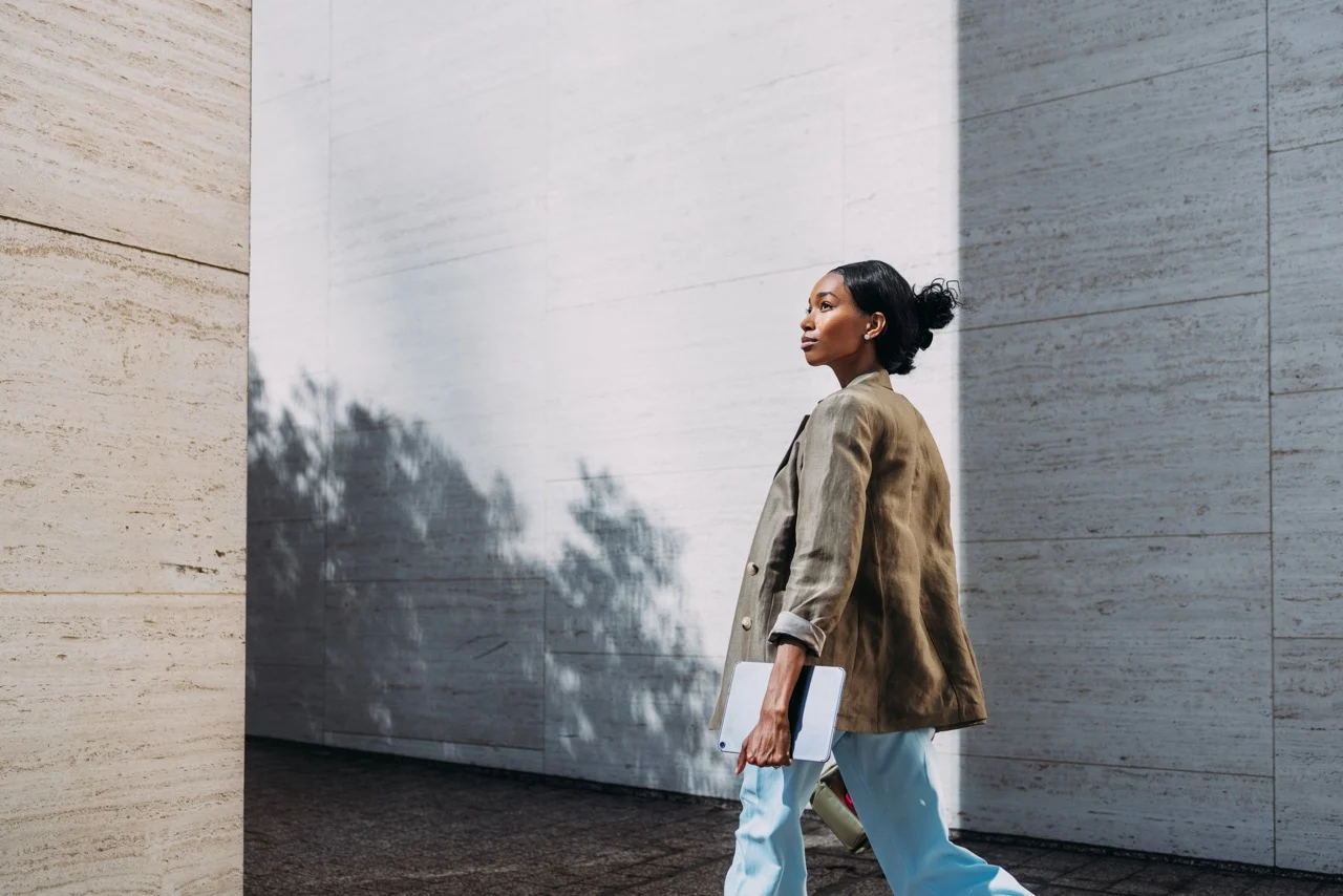 Executive walking with tablet in a modern urban setting, representing C-suite leadership, strategic counsel and navigating the intersection of business, policy and culture
