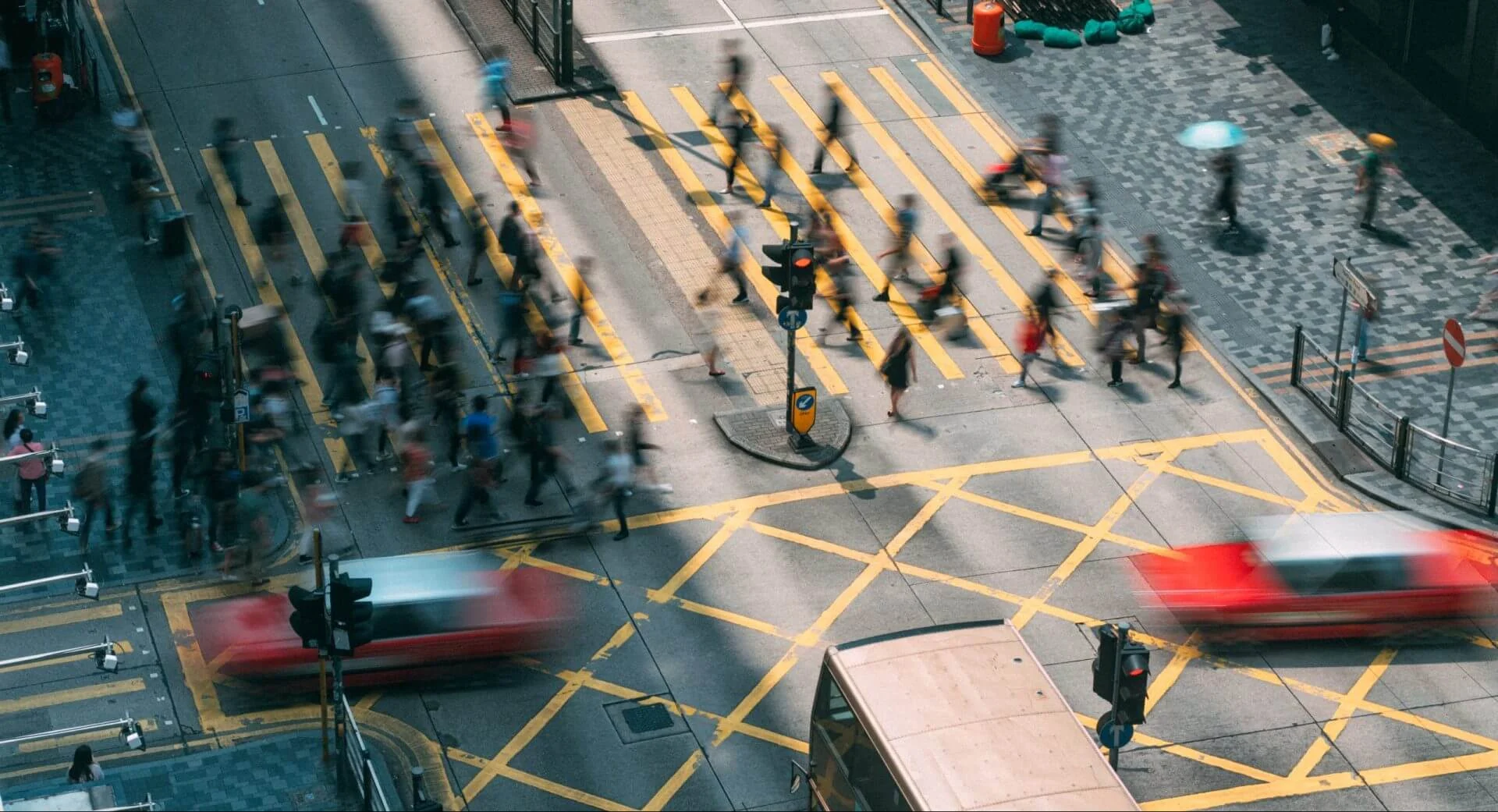 Busy urban intersection with blurred pedestrians and traffic crossing, symbolizing the intersection of business, technology, culture and society in a fast-moving world