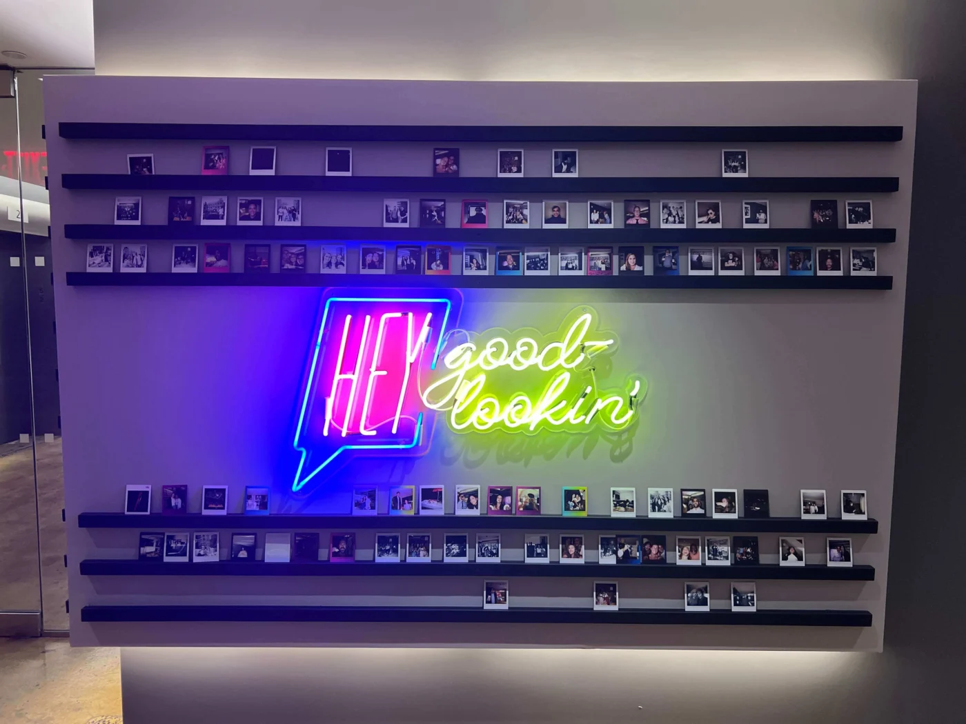 Weber Shandwick New York office interior featuring “Hey good lookin’” neon sign and photo wall, showcasing creative workplace culture