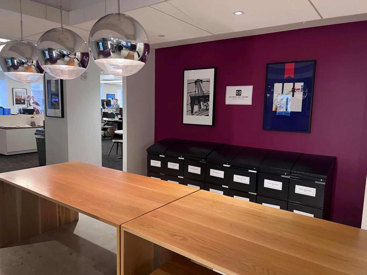 Weber Shandwick New York office mailroom area with wooden worktables, labelled storage units and pendant lighting in modern workspace