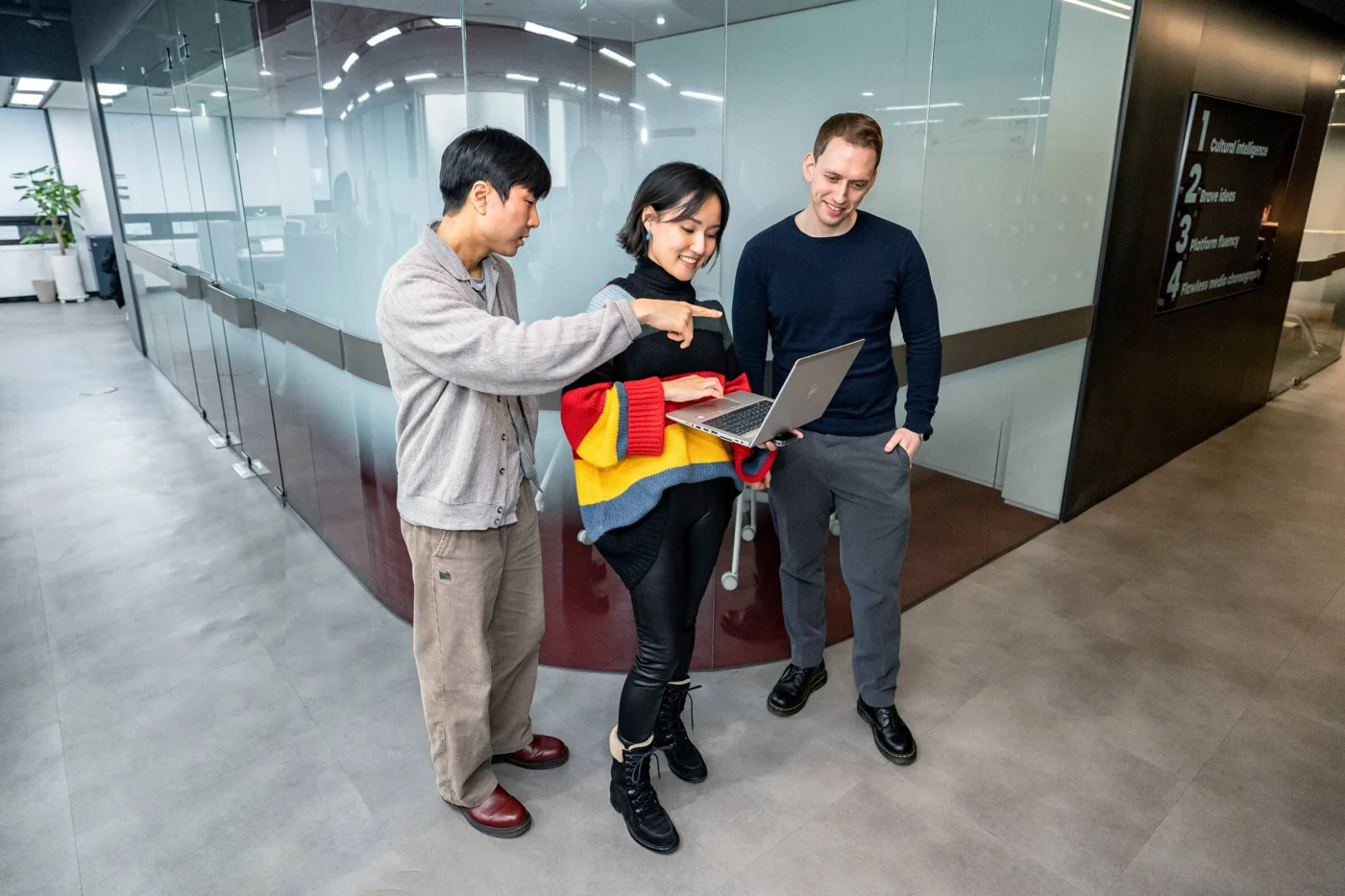 Weber Shandwick team members in Seoul office reviewing laptop together, showcasing collaboration and digital expertise in Gangnam Korea