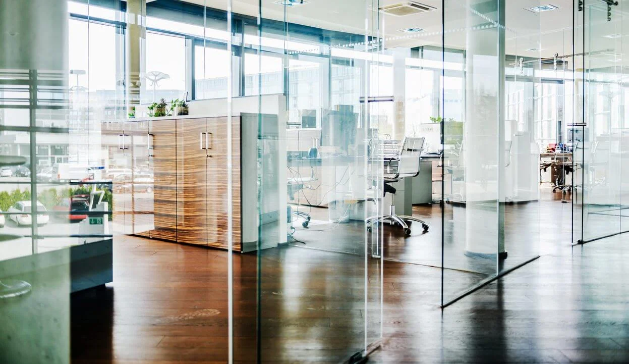 Modern open-plan office with glass walls and natural light, representing workplaces as hubs for well-being, collaboration and societal progress